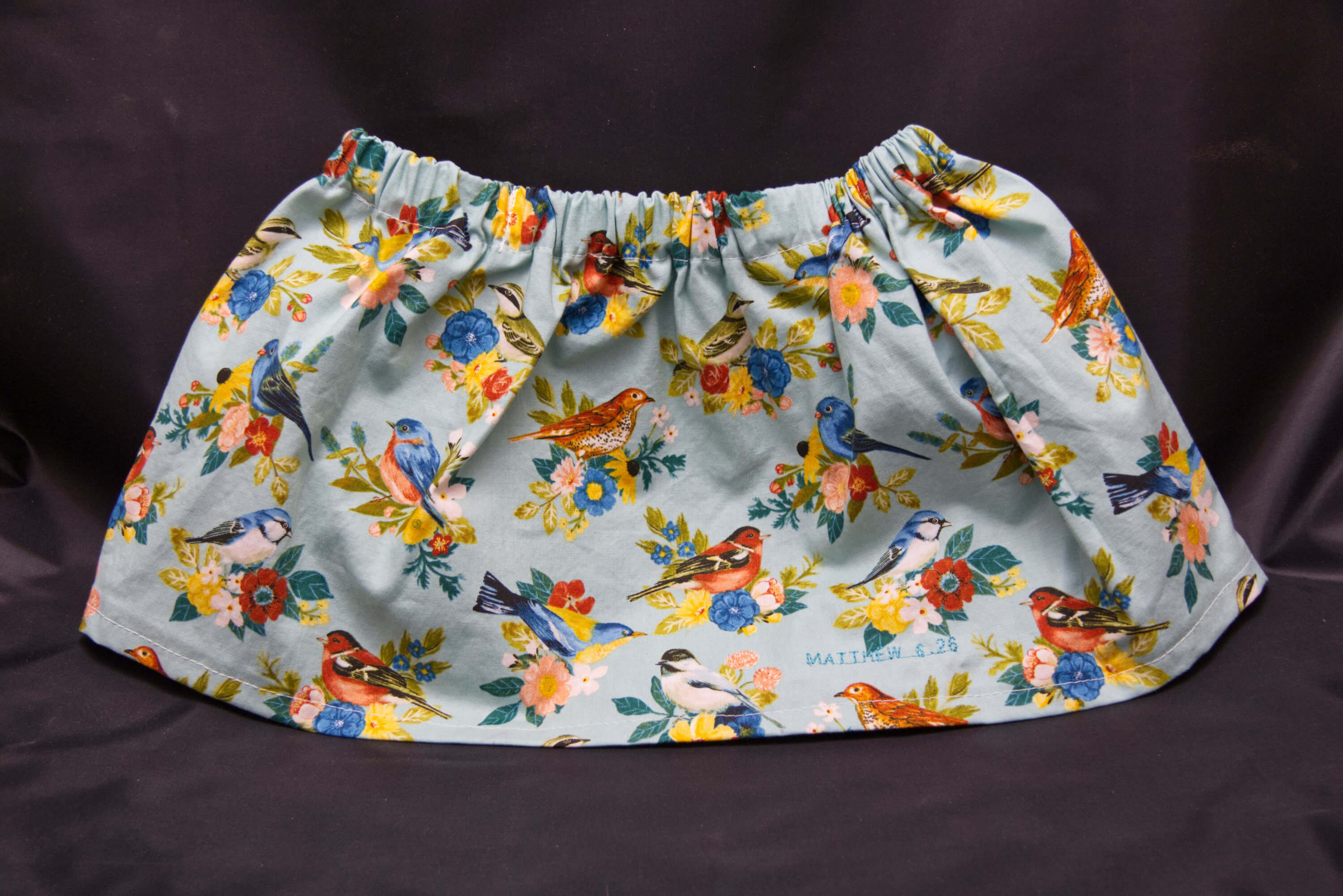 A light blue skirt with varius birds pirched on flowers.