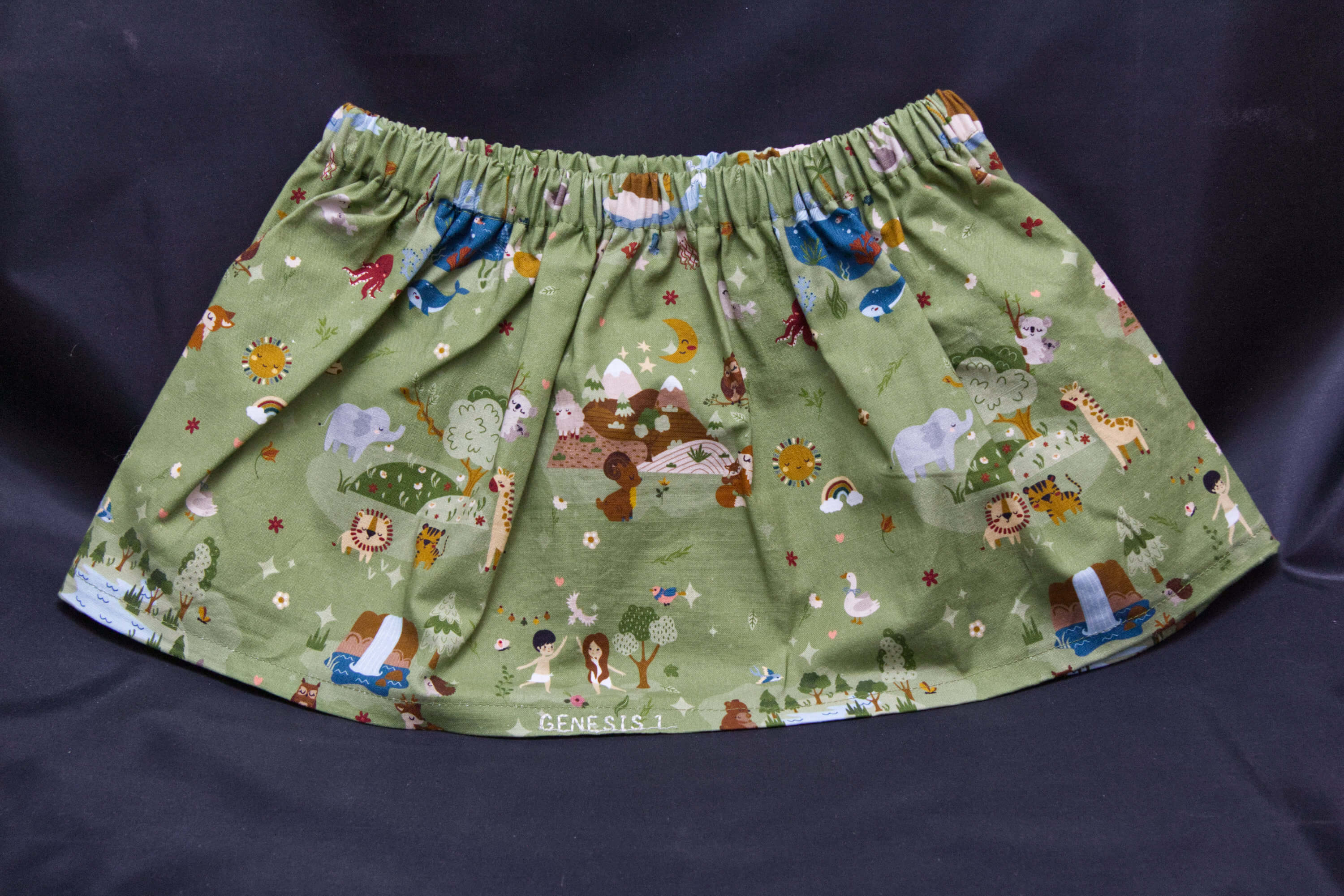 A green skirt with animals, birds, sea creatures and nature scenes on it.